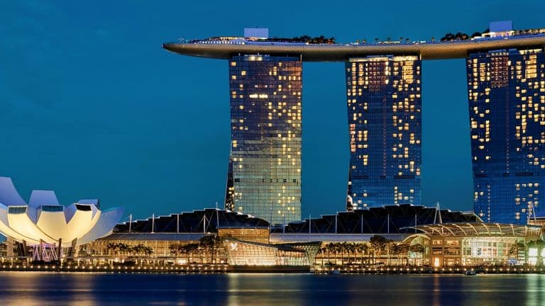 Marina Bay Sands hotel and casino, featuring its iconic three towers and a sky park atop, set against a clear blue sky.
