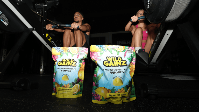 Wild Gainz creatine gummies displayed in a gym setting with athletes using rowing machines.