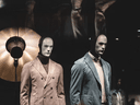 Mannequins wearing modern tailored menswear in a retail fashion display window.