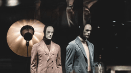 Mannequins wearing modern tailored menswear in a retail fashion display window.