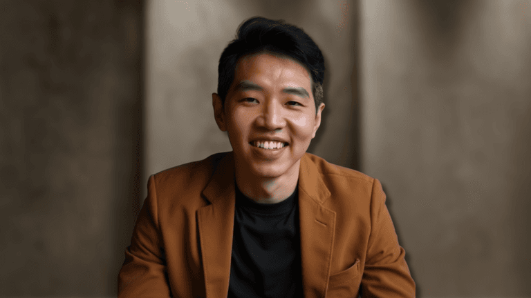 Dan Cheong, founder of Heroic Self, smiling confidently in a brown blazer and black shirt, embodying authenticity and purpose-driven transformation for men seeking self-discovery and personal growth