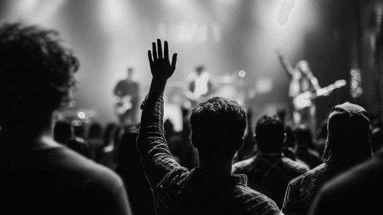 Man raising hand in crowd at worship event, symbolizing community, faith, and brotherhood central to Heart of a Man.