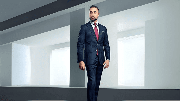 A confident man in a tailored pinstriped suit, standing in a modern, minimalist space with white walls and clean lines, exuding professionalism and sophistication.