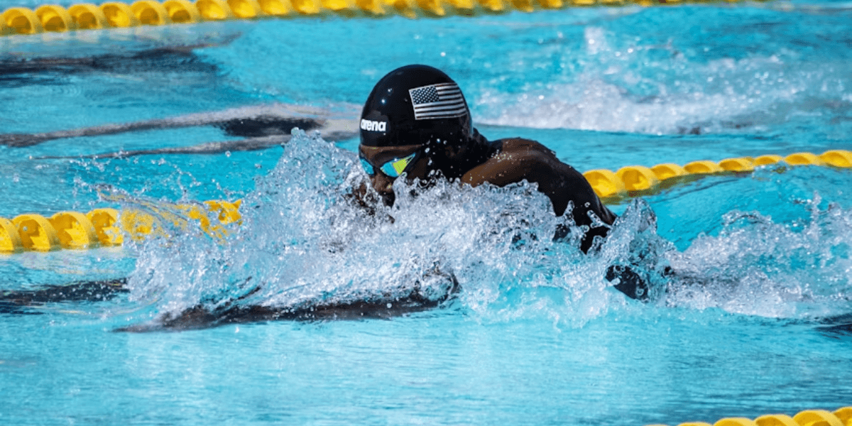 Competitive swimmer wearing a USA swim cap races in a pool during a championship event.
