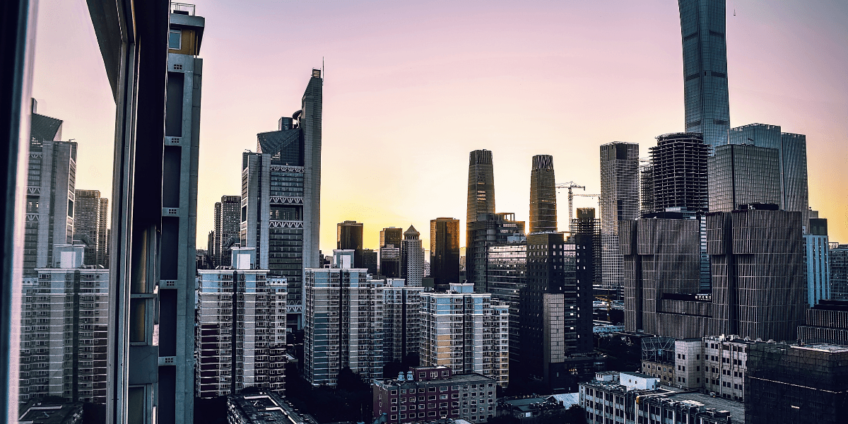 City skyline at sunset with tall buildings reflecting warm colors in the sky
