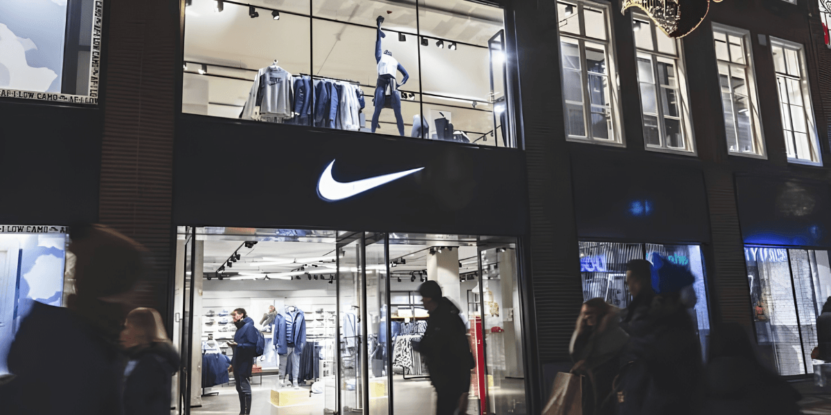Nike store at night with shoppers outside and clothing displays visible inside