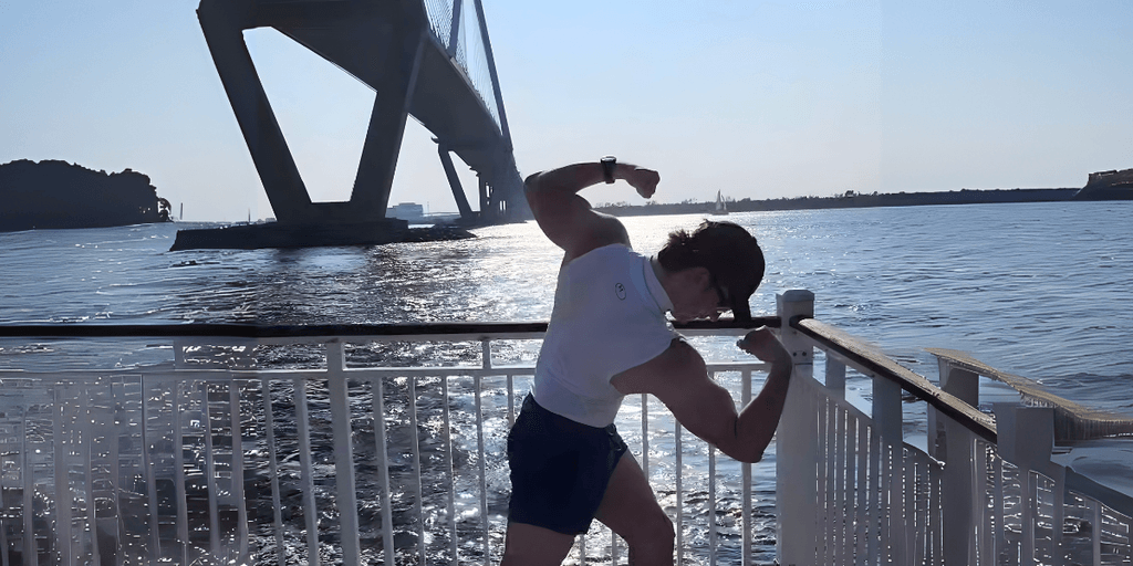 Brandon Stalter flexing by the water under a bridge, embodying strength, resilience, and transformation in his fitness journey.