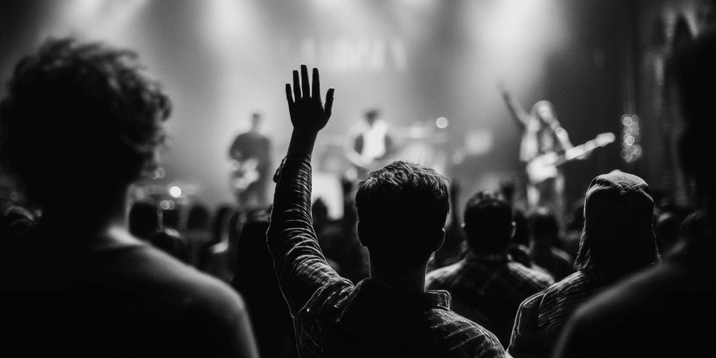 Man raising hand in crowd at worship event, symbolizing community, faith, and brotherhood central to Heart of a Man.