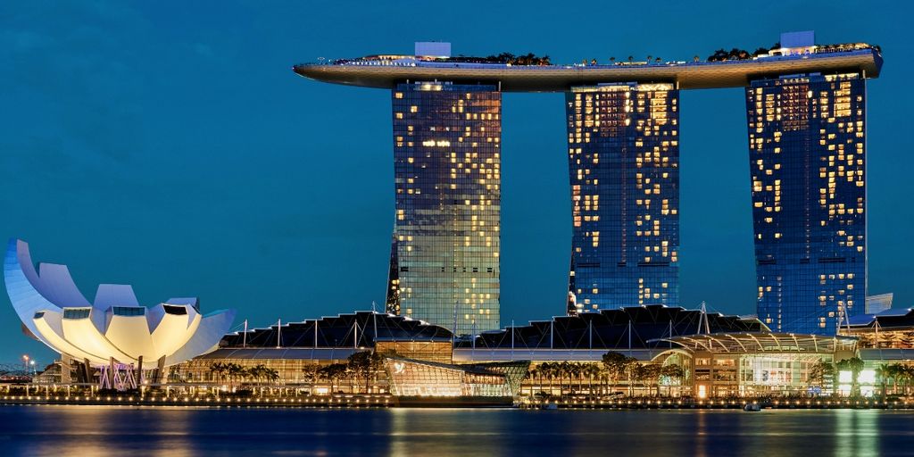 Marina Bay Sands hotel and casino, featuring its iconic three towers and a sky park atop, set against a clear blue sky.