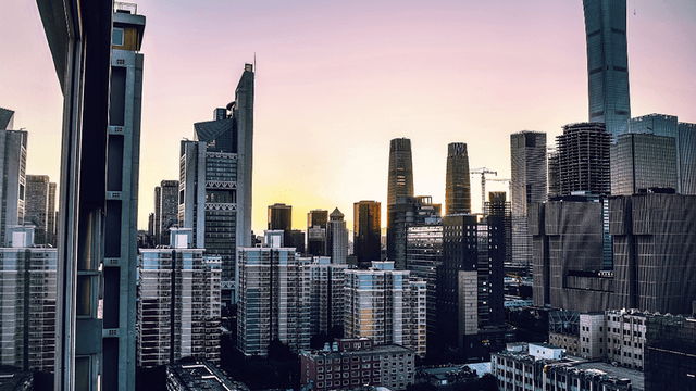 City skyline at sunset with tall buildings reflecting warm colors in the sky