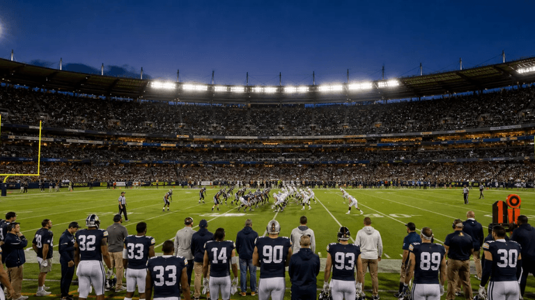 Evening football game in a packed stadium with players on the field