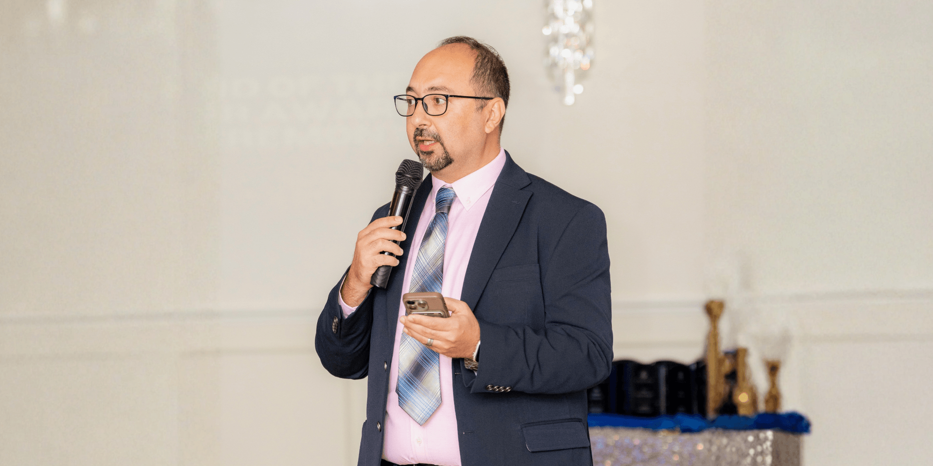 A man in a suit speaking into a microphone at an event