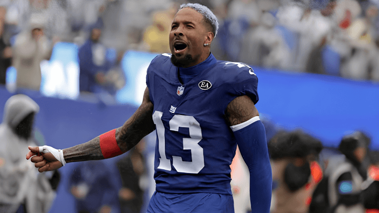 Football player in a blue jersey celebrates on the field with fans in the background