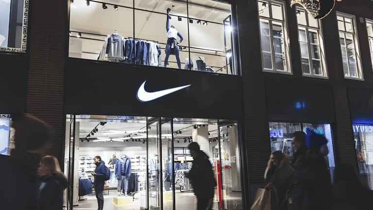 Nike store at night with shoppers outside and clothing displays visible inside