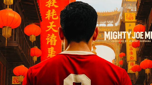 A man in a red jersey stands in a vibrant street decorated with lanterns.
