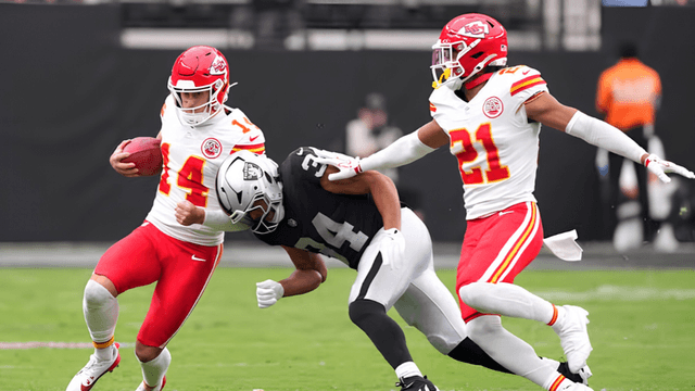 Football players in action during a game, one evading a tackle from two opponents