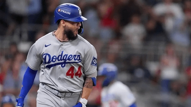 Baseball player celebrating a hit while wearing a Dodgers jersey and helmet
