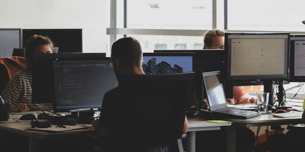 People working at desks with computers in a modern office environment