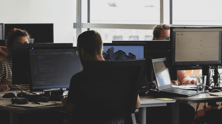 People working at desks with computers in a modern office environment