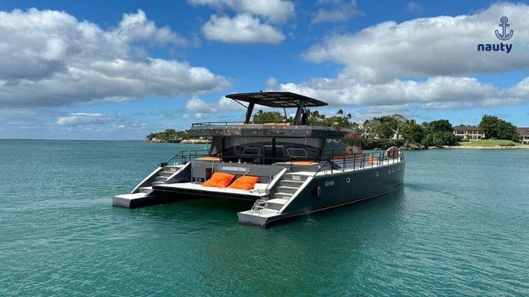 Modern catamaran floating on calm coastal waters beneath a partly cloudy sky.