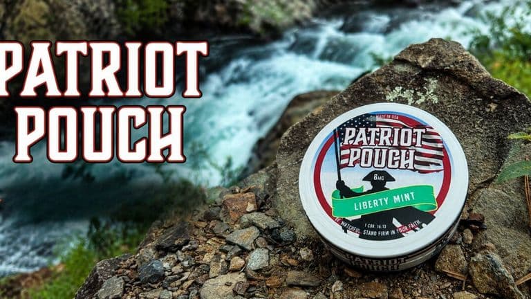 Patriot Pouch Liberty Mint nicotine-free oral pouch displayed on a rock beside a flowing mountain stream.