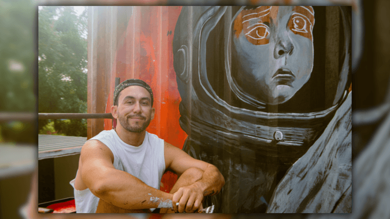 Michel Iniestra, a multidisciplinary artist, poses next to his emotional mural of an astronaut child, reflecting his creative vision.