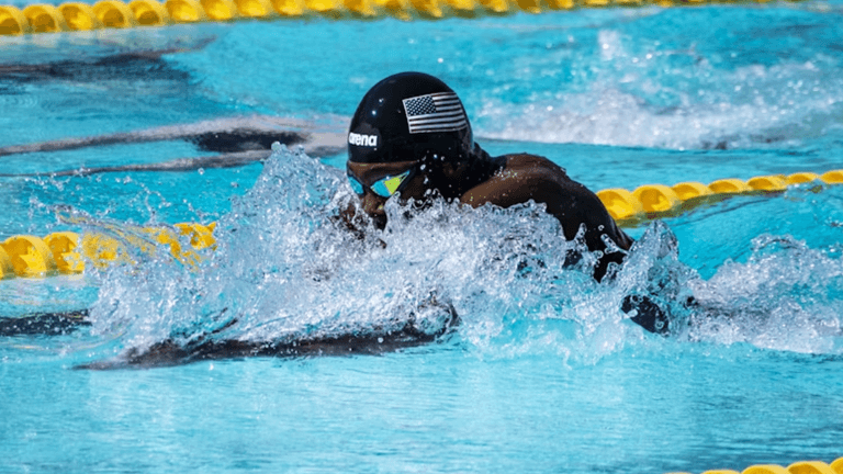 Competitive swimmer wearing a USA swim cap races in a pool during a championship event.