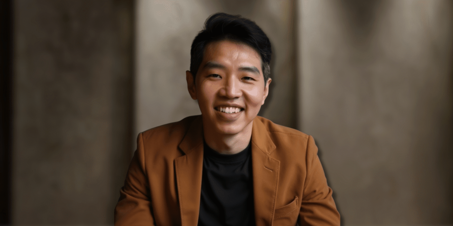 Dan Cheong, founder of Heroic Self, smiling confidently in a brown blazer and black shirt, embodying authenticity and purpose-driven transformation for men seeking self-discovery and personal growth