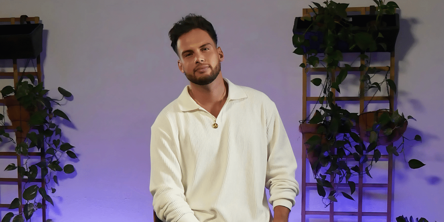 Ali Ozdemir sitting confidently in a studio with plants and purple lighting.
