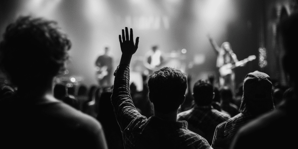 Man raising hand in crowd at worship event, symbolizing community, faith, and brotherhood central to Heart of a Man.
