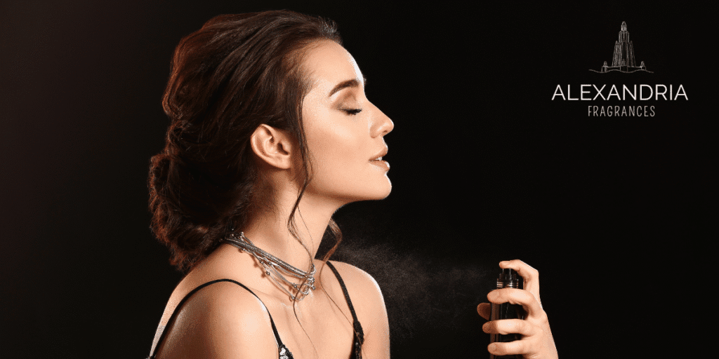 A woman sprays perfume from a bottle, eyes closed, with soft mist surrounding her, and Alexandria Fragrances logo in the corner.